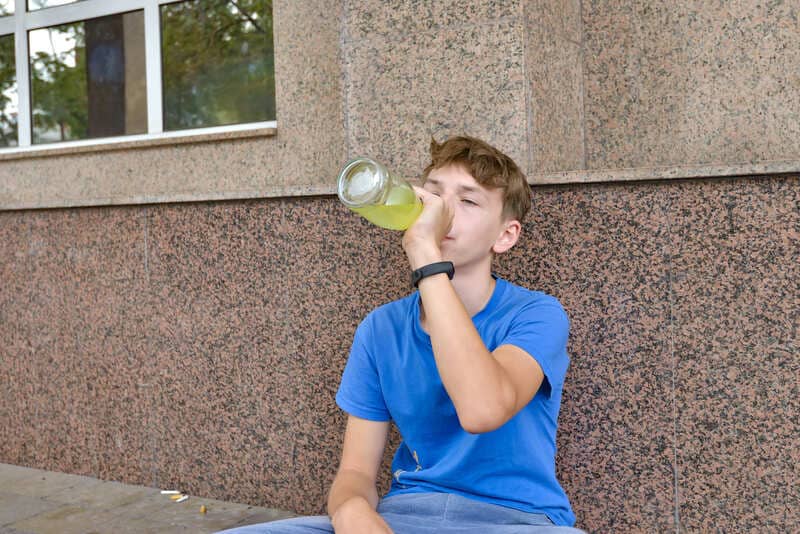 Подросток пьет алкоголь из бутылки
